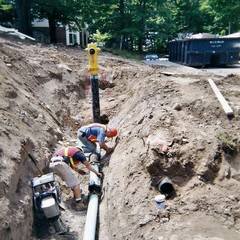 Workmen laying pipe in trench
